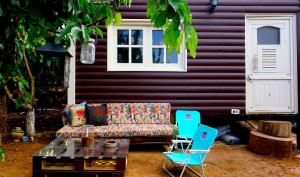 a couch and two chairs in front of a purple house at Cantina Cabin's - Think Nature in Mas'ada