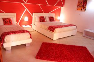 a bedroom with two beds with red pillows and a red rug at Del Cavaliere in Castrovillari