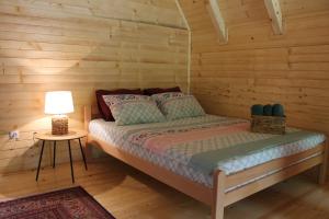 a bed in a log cabin with a lamp on a table at Nadiaa Wood House in Ilidža