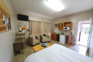 a bedroom with a bed and a desk and a kitchen at GlassTree B&B in Bredasdorp