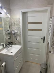 a white bathroom with a sink and a mirror at Apartament Bosmana in Darlowko