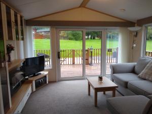 a living room with a couch and a television at Lazy Days Lodge in Glendevon