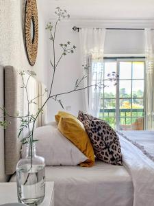 a bed with pillows and a vase on a table at Stylish 3 Bedroom Apartment close to the Beach in Monte Gordo