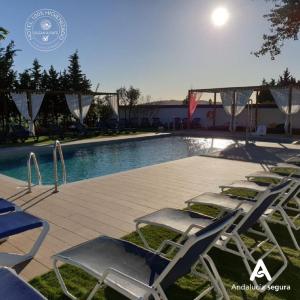 a group of lawn chairs next to a swimming pool at Hotel Restaurante La Villoría in Medina Sidonia