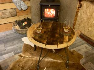 2 copas de vino en una mesa de madera con estufa de leña en The Bothy Aberlour en Aberlour