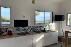 a kitchen with a counter with a sink and windows at Superbe appartement avec Terrasse et Vue in Bouzigues