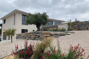 a house with a stone retaining wall and flowers at Superbe appartement avec Terrasse et Vue in Bouzigues