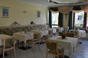 een restaurant met tafels en stoelen met witte tafelkleden bij Kurpension Gundula in Bad Füssing