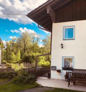 a white house with a wooden fence and a bench at Ferien an der Traun in Traunwalchen