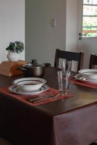 einem Tisch mit Tellern, einem Topf und einem Glas in der Unterkunft Apartamentos del Sol in San Carlos de Bariloche