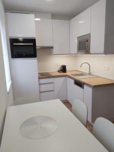 uma cozinha com armários brancos e uma mesa com cadeiras em Hello apartman em Eger