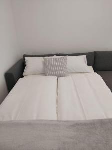 Una cama con sábanas blancas y almohadas. en Hello apartman, en Eger