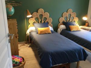 a bedroom with two beds with blue and yellow pillows at Le Cottage des Mésanges in Villefranche-de-Rouergue