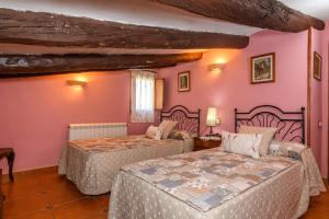 a bedroom with two beds and pink walls at Casa lo Ferre in Beceite