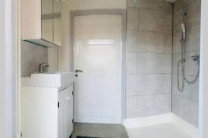 a white bathroom with a shower and a sink at Cosy house in the heart of the center! in Oostburg