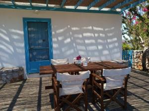 una mesa de madera y sillas en un porche con puerta azul en Kasi's nature home en Kýthira