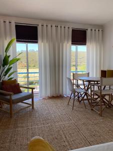 ein Wohnzimmer mit einem Tisch, Stühlen und Fenstern in der Unterkunft Casa da Várzea in Odeceixe