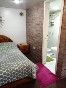 1 dormitorio con cama y pared de ladrillo en Mini suites en el mejor sector de la ciudad, en Quito