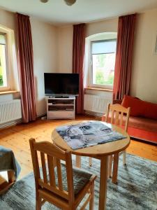 een woonkamer met een tafel en stoelen en een televisie bij Apartament Albion in Szklarska Poręba