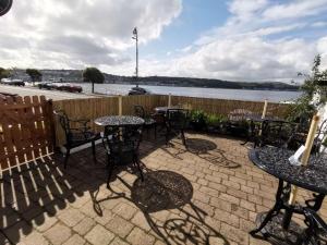 a patio with tables and chairs and a body of water at Summer's Bay in Rothesay