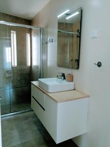 a white bathroom with a sink and a shower at Casa Doce in Olhão