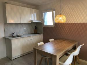 una cucina con tavolo in legno e armadietti bianchi di Bovec Apartment a Bovec