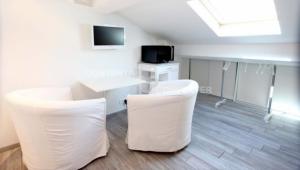 カンヌにあるAppartements Cannes Centre Villeの白い椅子、テーブル、テレビが備わる客室です。