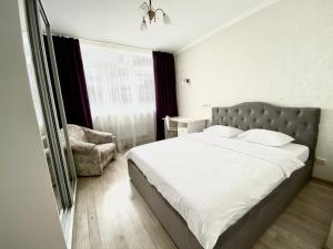 a bedroom with a large bed and a chair at Apartments with Dnipro view in Kyiv