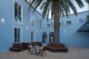 a palm tree in front of a building with a table and chairs at Casa do Pateo - Charming House Azores in Ponta Delgada