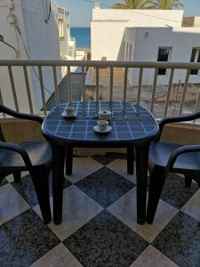 Una mesa y sillas azules en un balcón con la playa. en Apartamentos El Galán, en Carboneras