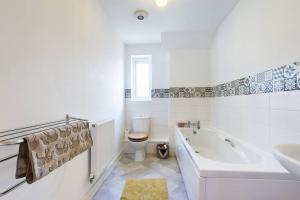 a bathroom with a tub and a toilet and a sink at Chic City Centre Apartment With Allocated Parking in Swansea +11 photos