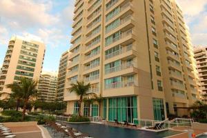 ein großes Gebäude mit einem Pool davor in der Unterkunft Apê na Barra, ao lado do Parque Olímpico, Jeunesse Arena, ar, wi fi, tv a cabo, microondas in Rio de Janeiro