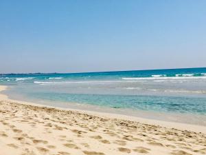 une plage avec des empreintes sur le sable et l'océan dans l'établissement Villa Ale., à Pulsano