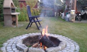 a fire pit with a chair in a yard at BURSZTYN 3 in Rusinowo