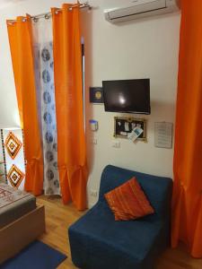 Wohnzimmer mit orangefarbenen Vorhängen und blauem Sofa in der Unterkunft La Casetta in Palermo