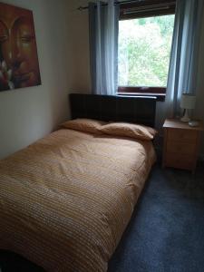 1 cama en un dormitorio con ventana y colcha en Loch View, en Fort William