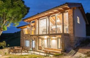a stone house with a balcony and a table at Pulieru - Picos de Europa views, designed for all seasons in Cangas de Onís