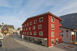 un edificio rojo al lado de una calle en 3,5 Zimmer Dachwohnung: Modern, komfortabel, zentral, mit Bergsicht, en Disentis