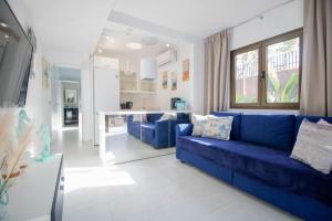 een woonkamer met een blauwe bank en een keuken bij Bungalow Portos with amazing privet garden in Playa del Inglés