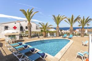 una piscina con sillas, palmeras y el océano en Villa Lali en Arenal d'en Castell
