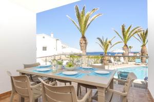 a dining room with a table and chairs and palm trees at Villa Lali in Arenal d'en Castell