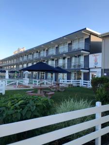 hotel ze stołami i parasolami przed nim w obiekcie Yankee Clipper Resort Motel w mieście Wildwood Crest