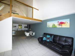 a living room with a black leather couch and a kitchen at Canopy Chalet 10 in Nelly Bay