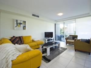 a living room with a yellow couch and a tv at Blue on Blue Apartment 921 in Nelly Bay