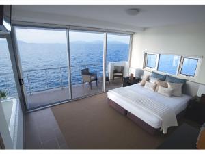 a bedroom with a bed and a balcony with the ocean at 1 Bright Point Apartment 5201 in Nelly Bay