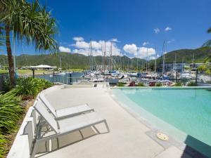 a swimming pool next to a marina with boats at Blue on Blue Superior Studio Room 1321 in Nelly Bay