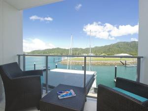 a balcony with a table and chairs and a view of the water at Blue on Blue Studio Room 1242 in Nelly Bay
