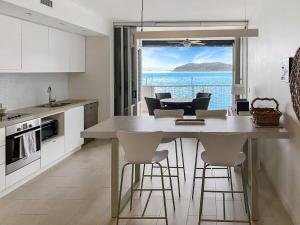 eine Küche mit einem Tisch und Stühlen sowie Meerblick in der Unterkunft 1 Bright Point Apartment 2303 in Nelly Bay