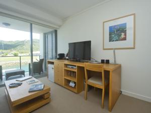 ein Wohnzimmer mit einem Schreibtisch und einem TV in der Unterkunft Blue on Blue Studio Room 1242 in Nelly Bay