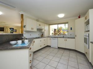 a large kitchen with white cabinets and a window at Island Dreams in Nelly Bay